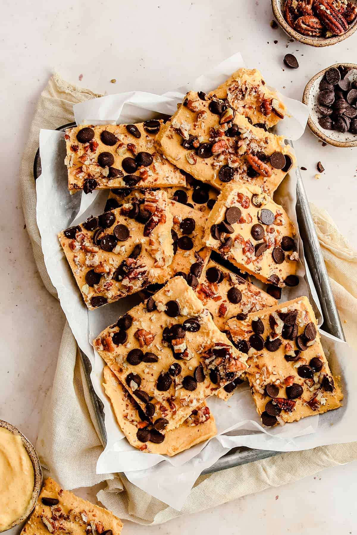 low carb yogurt bark cut into squares on a sheet pan topped with nuts and chocolate chips