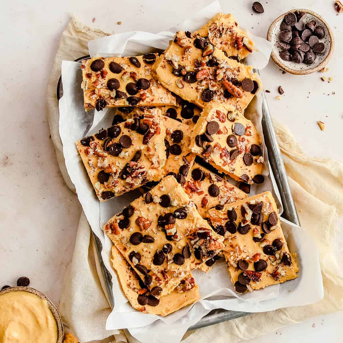 low carb yogurt bark cut into squares on a sheet pan topped with nuts and chocolate chips
