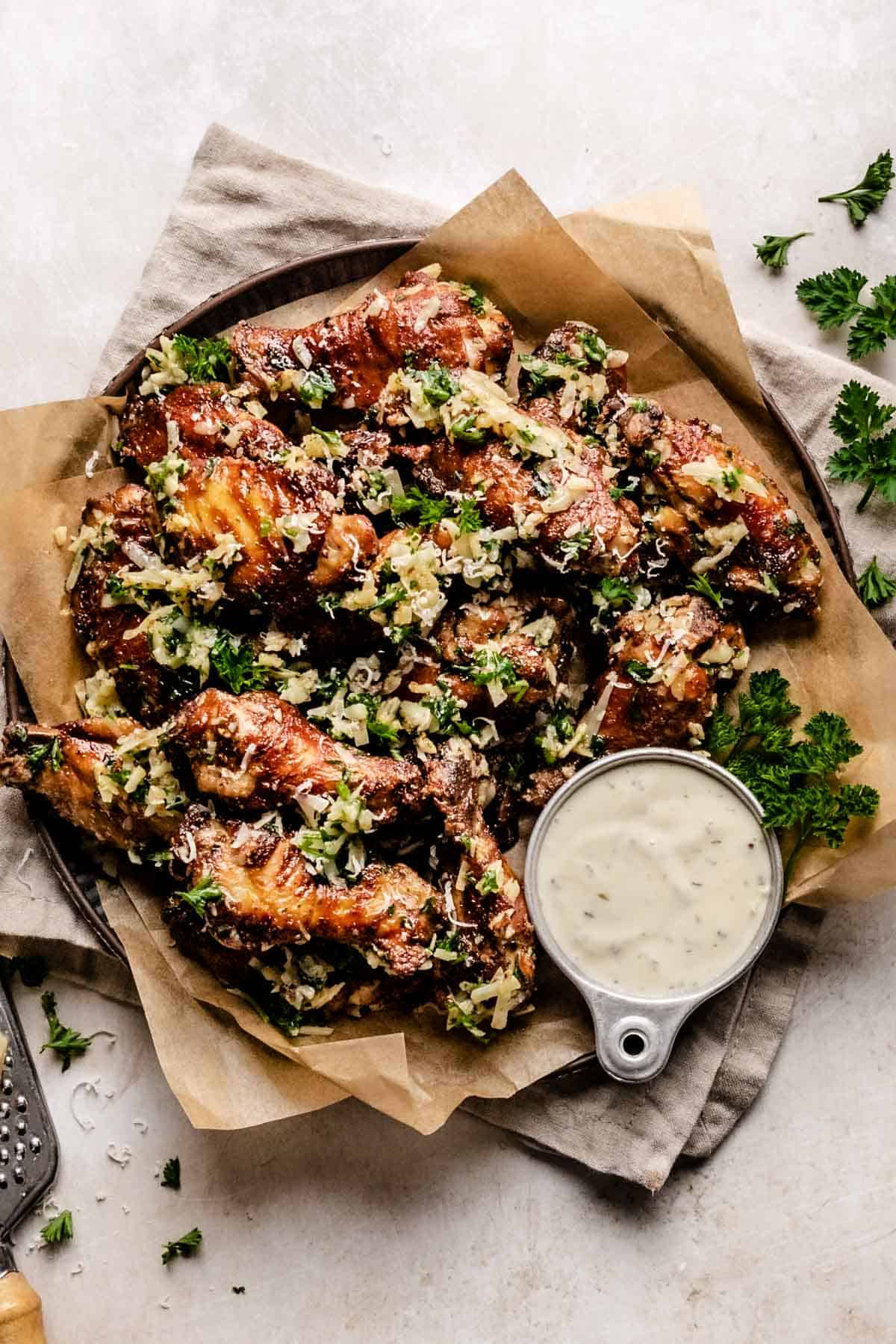 a platter filled with garlic parmesan keto chicken wings with a metal bowl filled with ranch dressing 