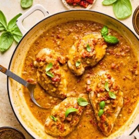 marry me chicken in a skillet topped with fresh basil