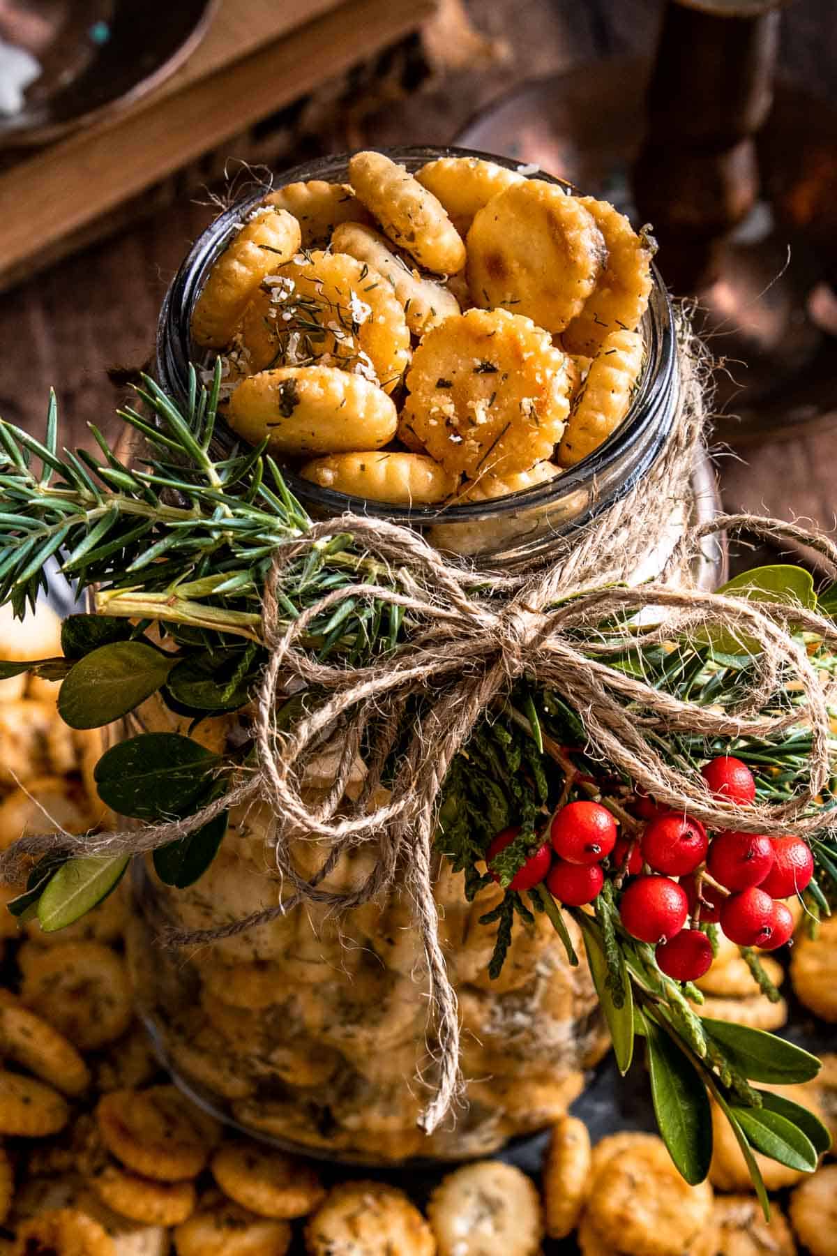 a holiday decorated mason jar filled with seasoned oyster crackers. 