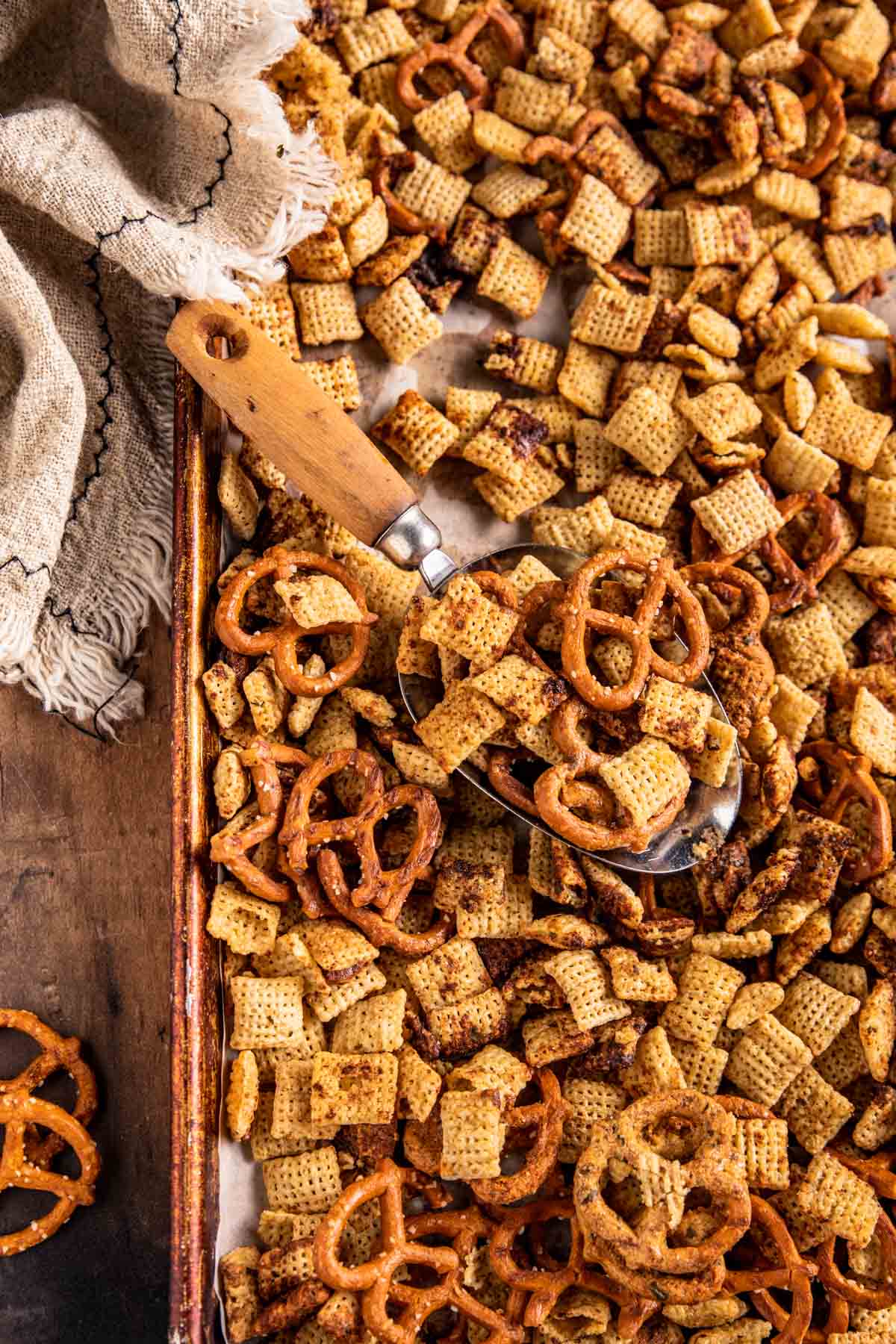 a baking sheet filled with chex cereal and twist pretzels. 
