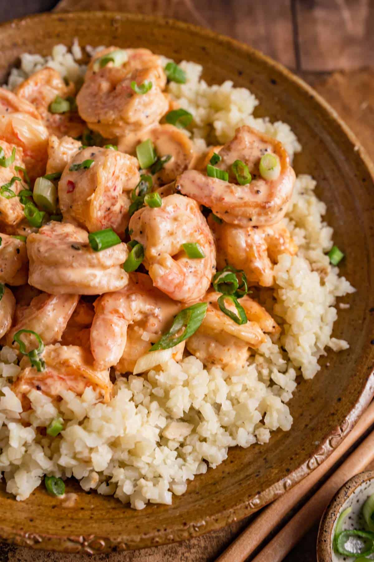 shrimp on top of cauliflower rice with chopped green onions on top.