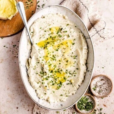 an overhead photo of keto mashed cauliflower in an oval serving platter
