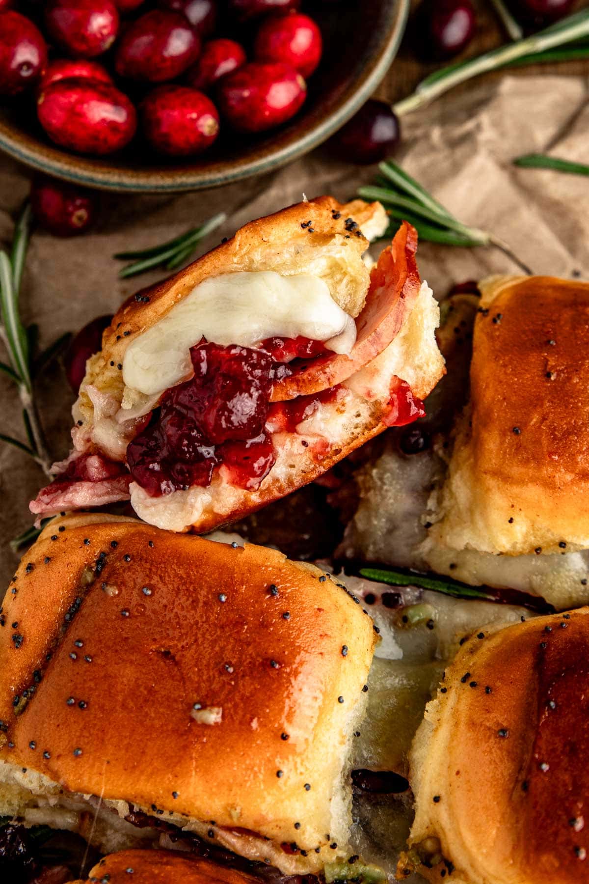 a side view of a turkey slider filled with cranberry sauce, turkey, and white cheese. 