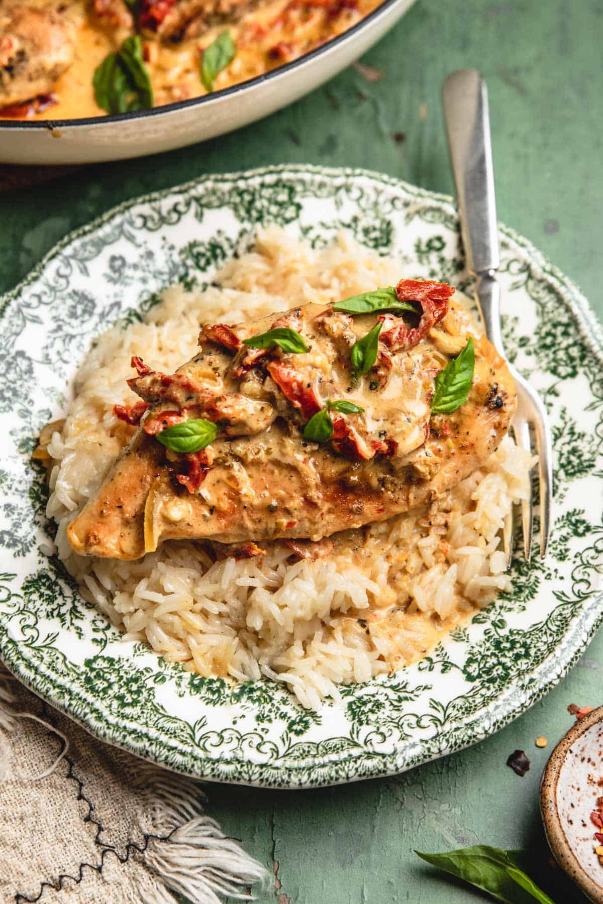 a plate filled with white rice and chicken topped with sun-dried tomatoes and fresh basil