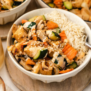 a bowl filled with white rice, hibachi chicken and vegetables and drizzled with yum yum sauce.