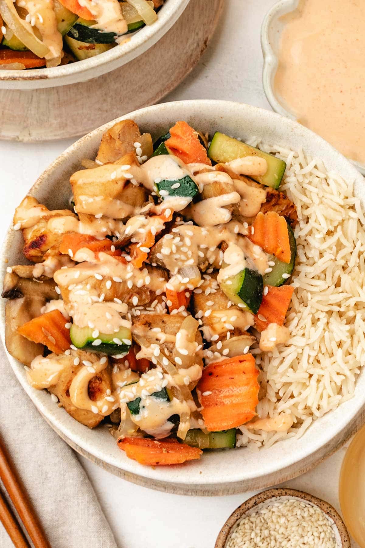a bowl filled with white rice, hibachi chicken and vegetables and drizzled with yum yum sauce. 