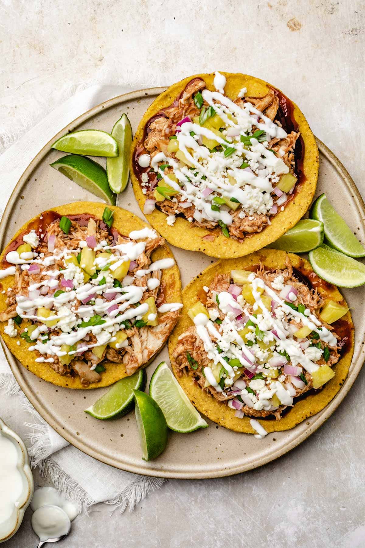 an overhead view of bbq chicken tostadas topped with lime crema on a plate