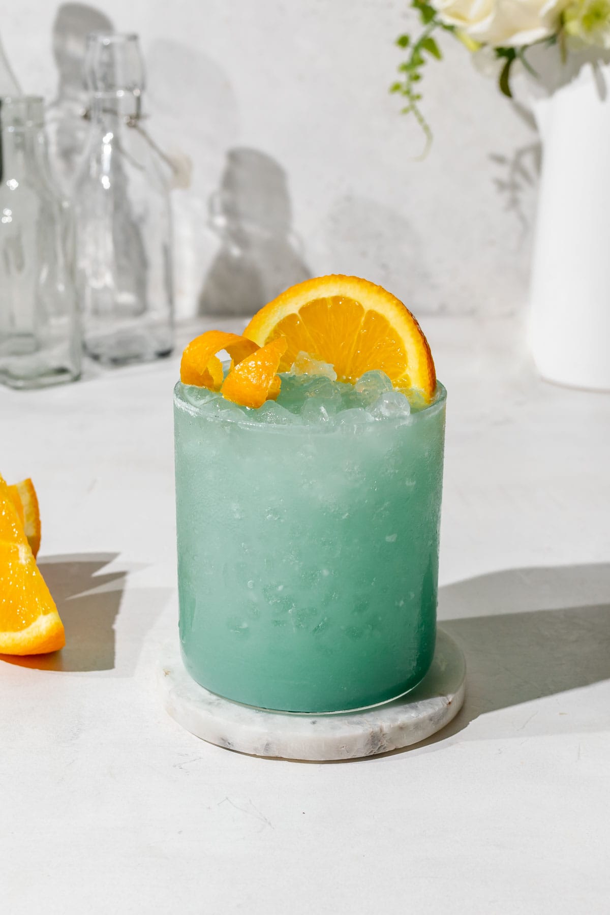 a blue Hawaiian mocktail in a highball glass topped with an orange wedge. 