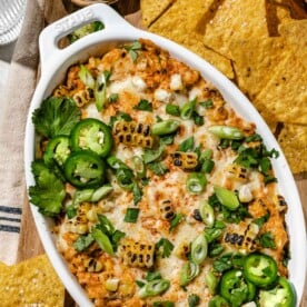 an overhead shot of mexcian street corn dip topped with cilantro, onions, and jalapenos.