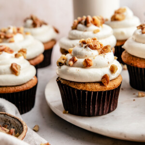 an up close photo of gluten-free cupcakes topped with frosting and crushed walnuts.