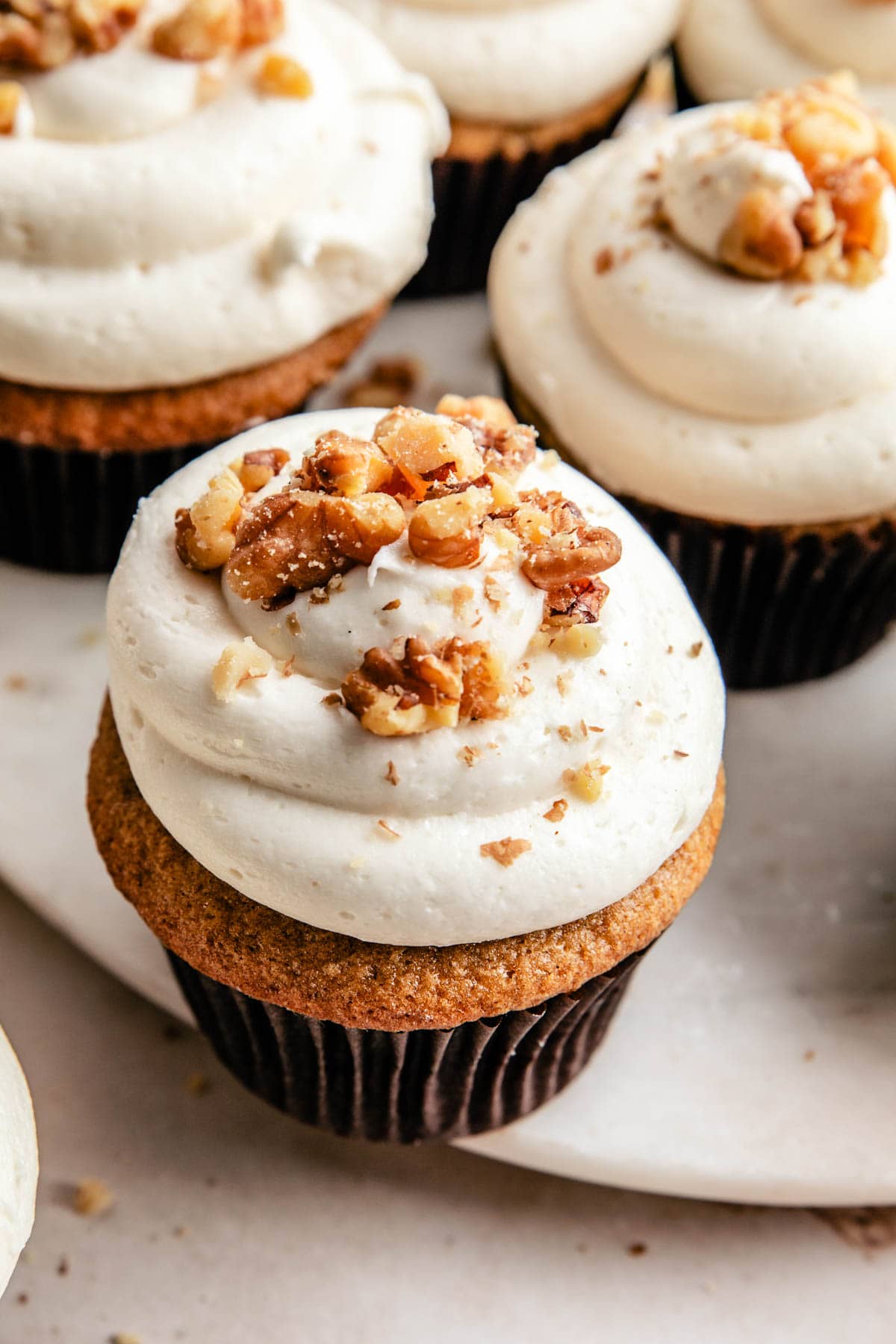 an overhead photo of carrot cake cupcakes topped with crushed walnuts