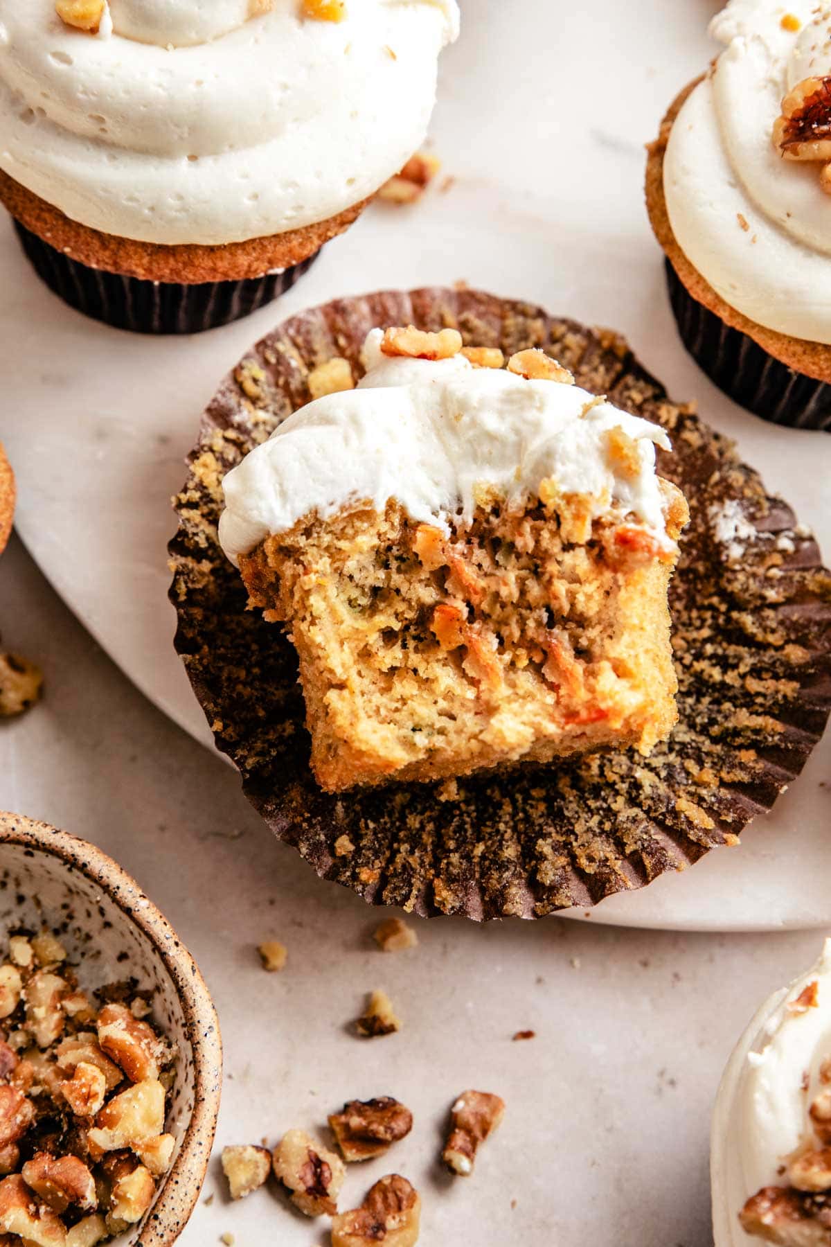 half of a carrot cake cupcake showing the middle and frosted top. 