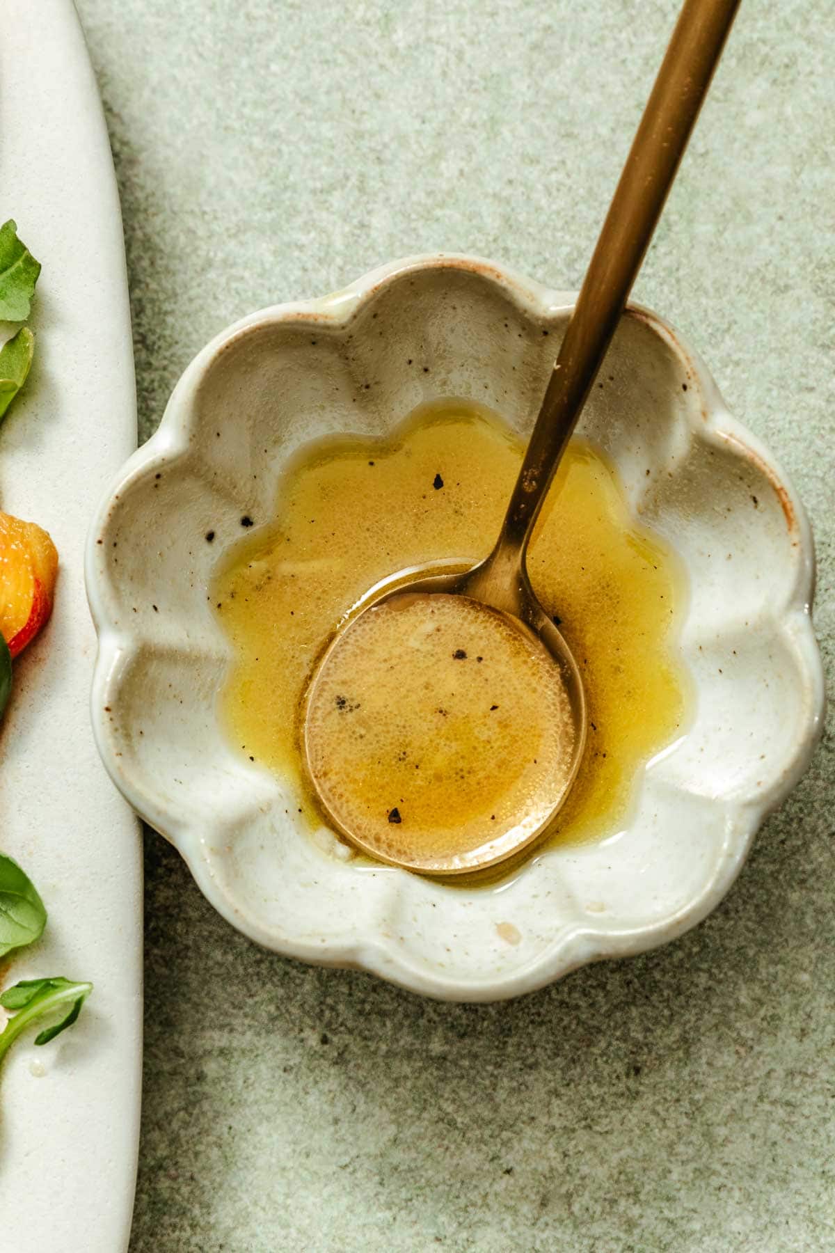 a small scalloped bowl with a spoon and salad dressing