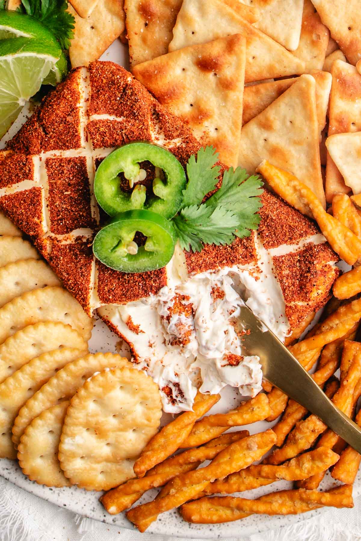a block of taco smoked cream cheese topped with sliced jalapenos and surrounded by crackers