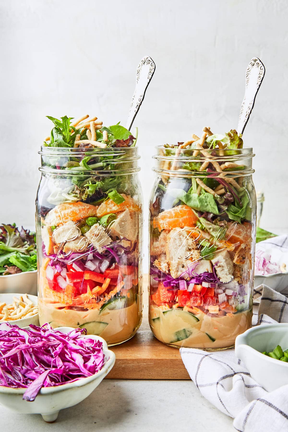 two Asian chicken mason jar salads next to each other on a cutting board. 
