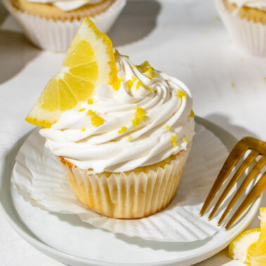 a lemon cupcake topped with dairy free cream cheese frosting and topped with a lemon slice