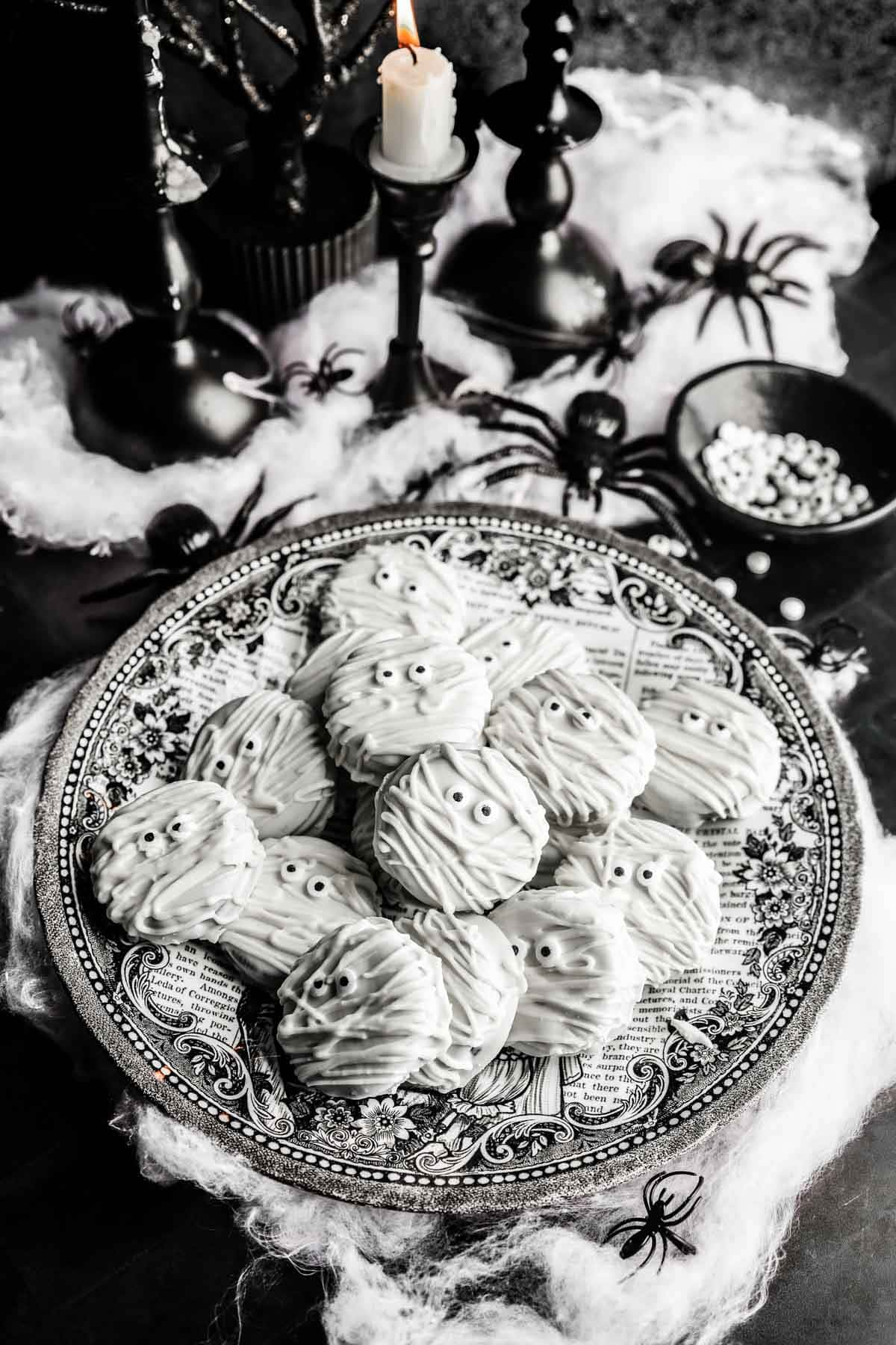 the cookies on a plate with spider webs and black candles. 
