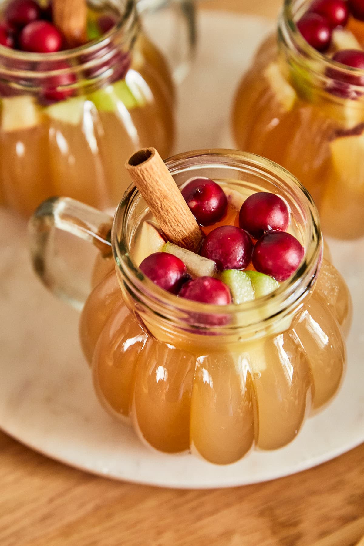 an overhead shot of a caramel apple drink topped with apples and whole cranberries