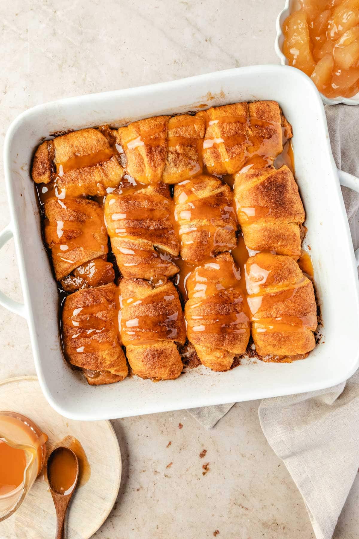 Mini apple pies in a large casserole dish drizzled with caramel