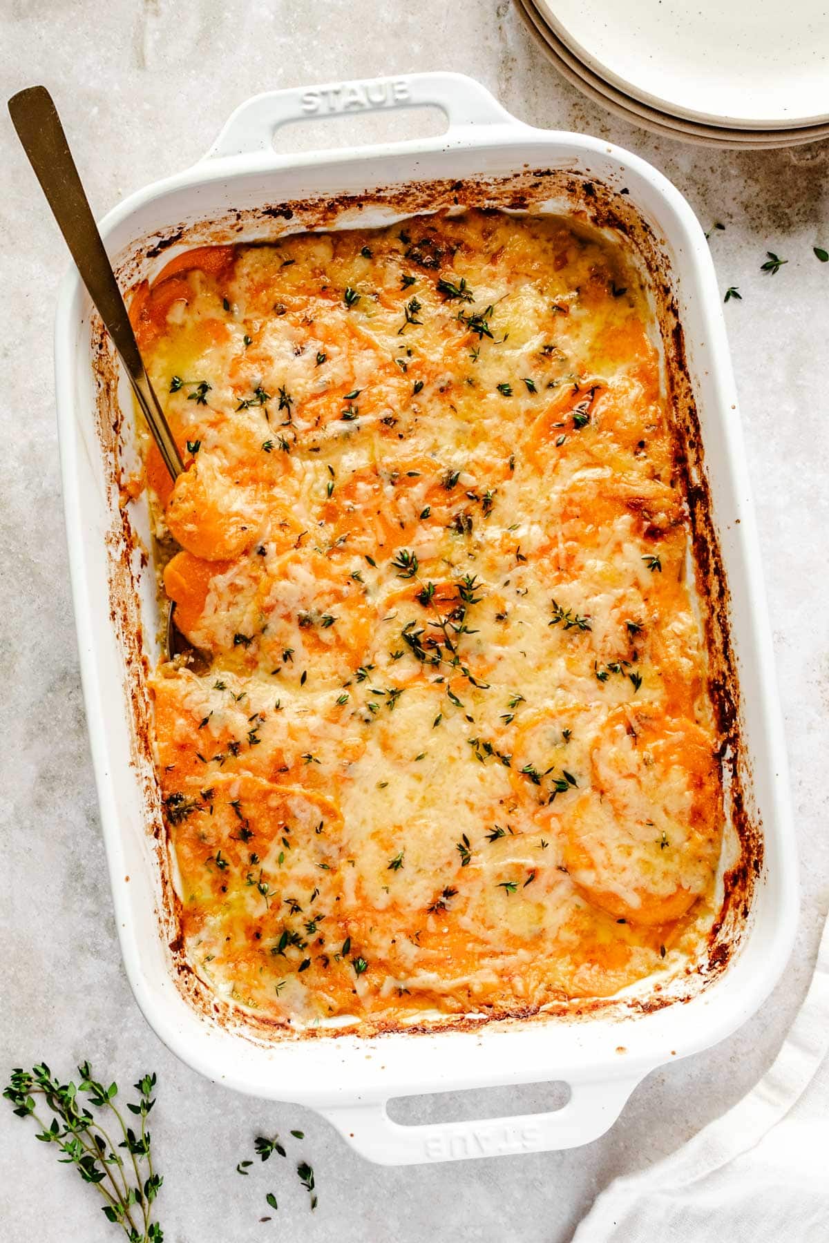 overhead shot of a sweet potato au gratin casserole topped with fresh thyme