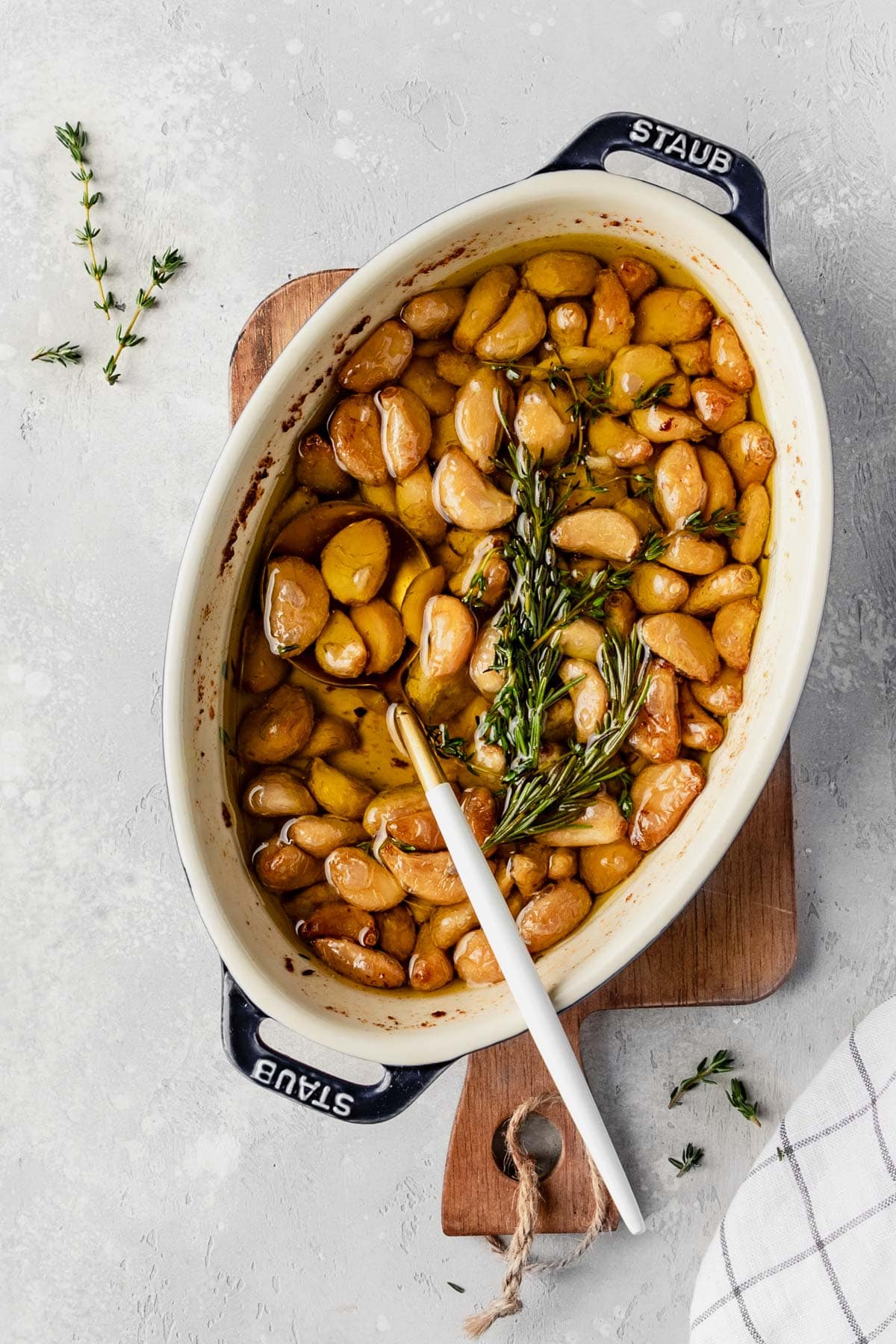 garlic confit in an oval baking dish topped with rosemary