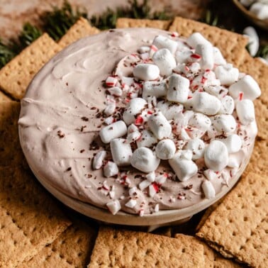 hot chocolate dip in a bowl topped with marshmallows and peppermint candies