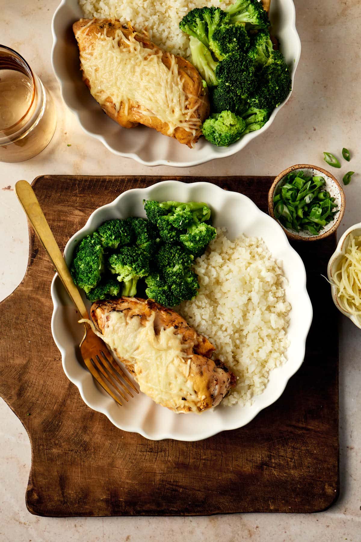 an overhead shot of cast iron chicken next to broccoli and cauliflower rice on a white plate