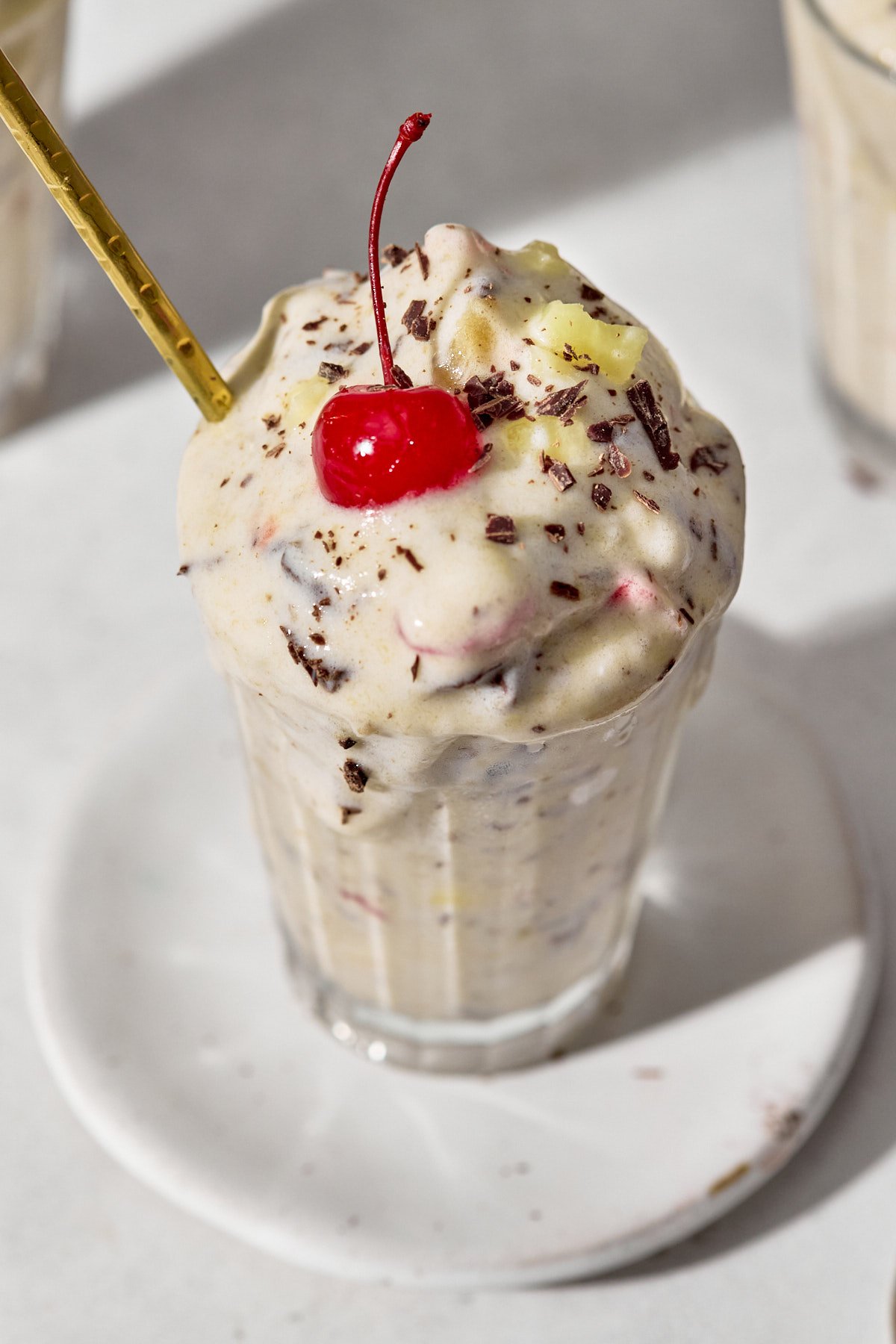 a close up shot of a banana split blizzard with a cherry on top and a gold straw