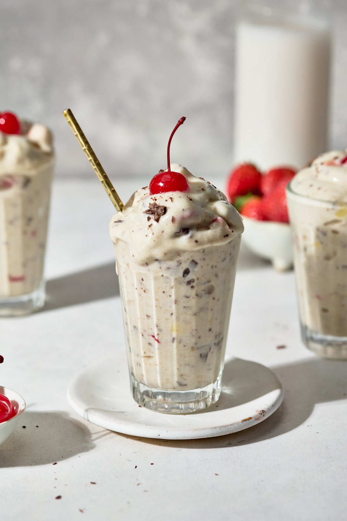 a banana split blizzard in a glass with a cherry on top