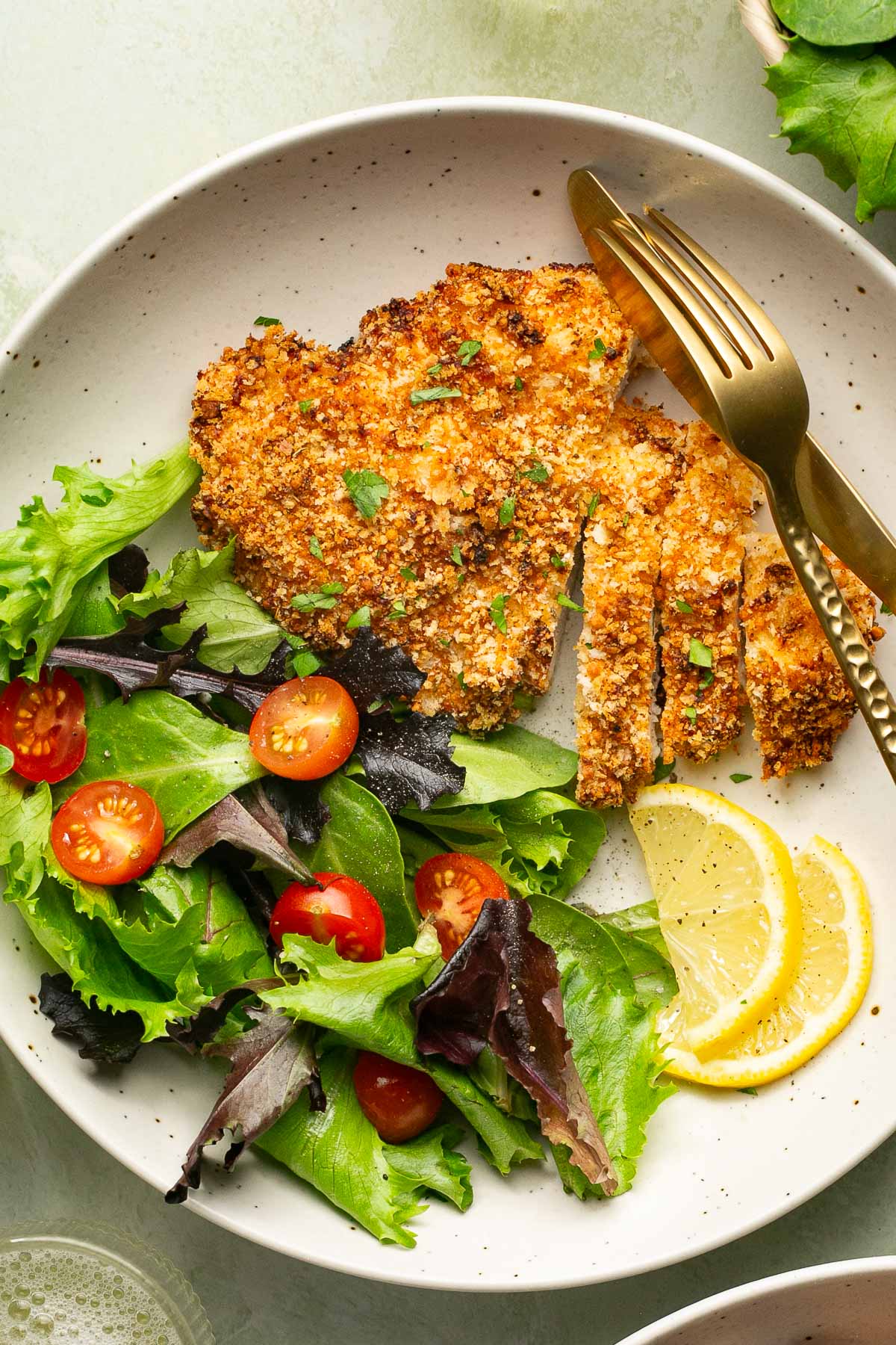 an overhead shot of air fryer chicken cutlets on a plate with a side salad