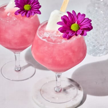 a strawberry coconut mocktail with a popsicle and flower on top