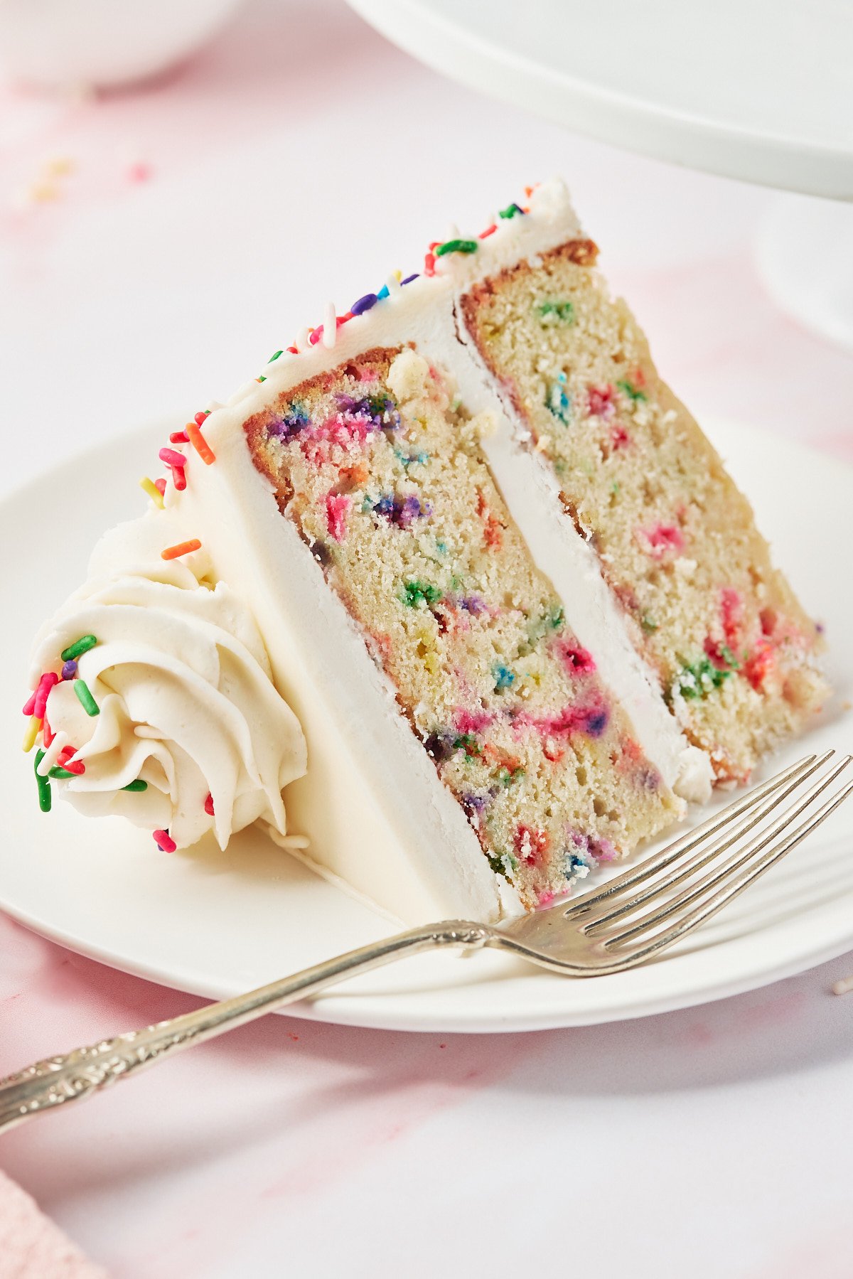 a slice of gluten-free funfetti cake on a white plate with a fork