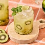 a close up shot of a kiwi mojito topped with mint