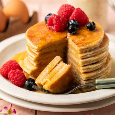 a stack of protein pancakes recipe on a plate with syrup and fresh berries on top