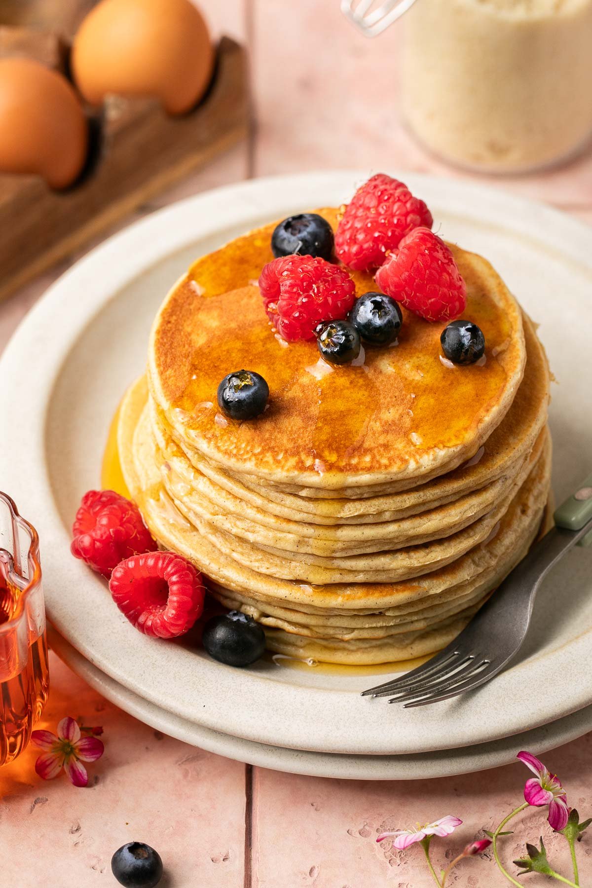 a stack of protein pancakes with fresh berries and syrup