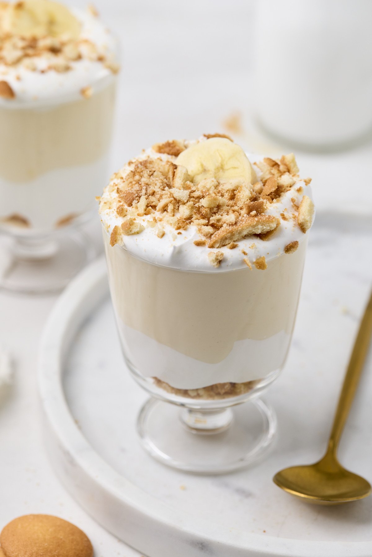 an overhead shot high protein Banana Pudding in a cup topped with whipped cream and crushed wafers