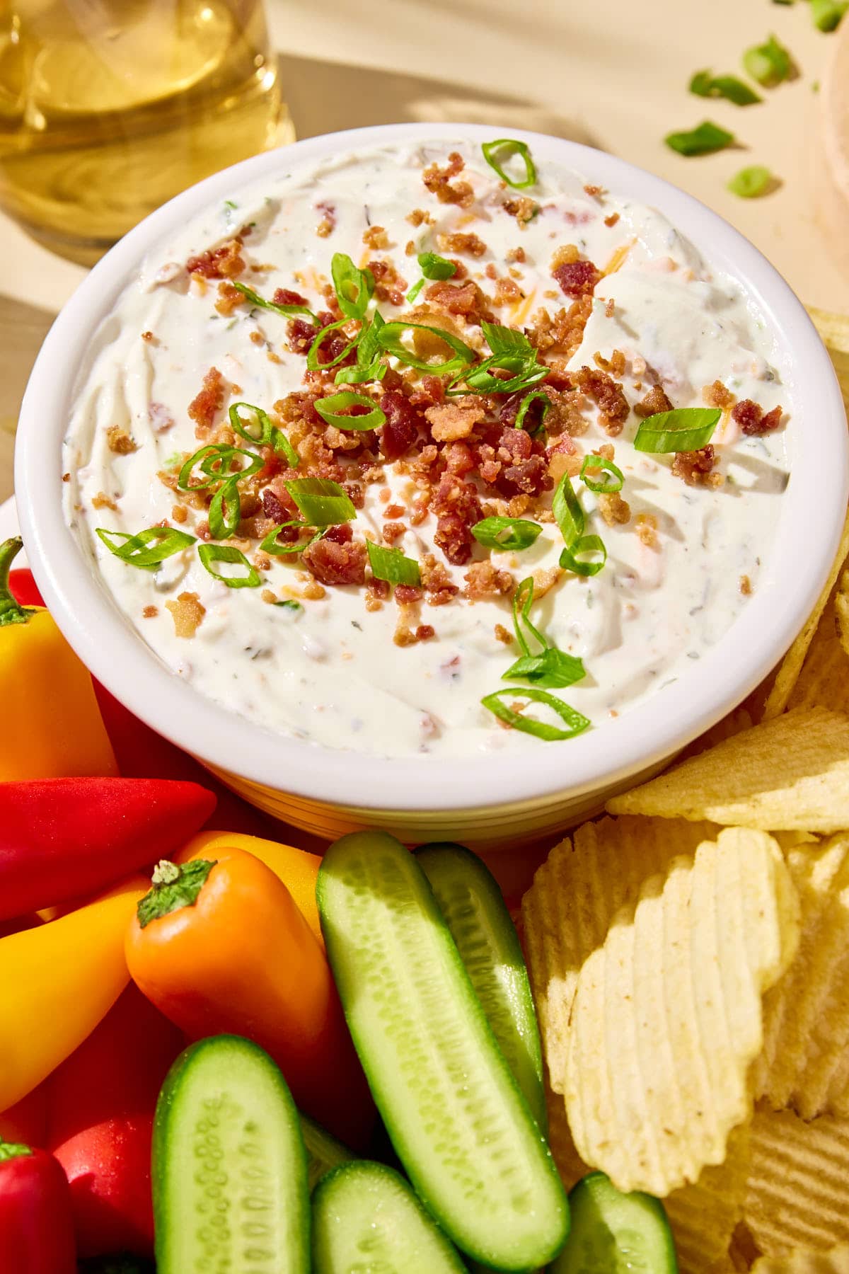 a close up of the healthy crack dip in a bowl garnished with green onions and chopped bacon