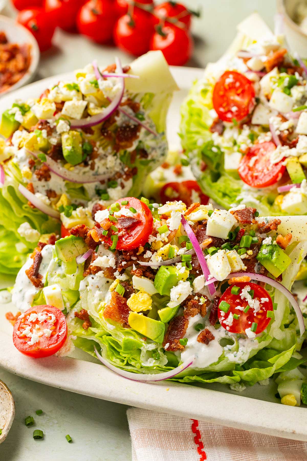 lettuce wedges topped with bacon, tomatoes, cheese, avocado, and ranch dressing