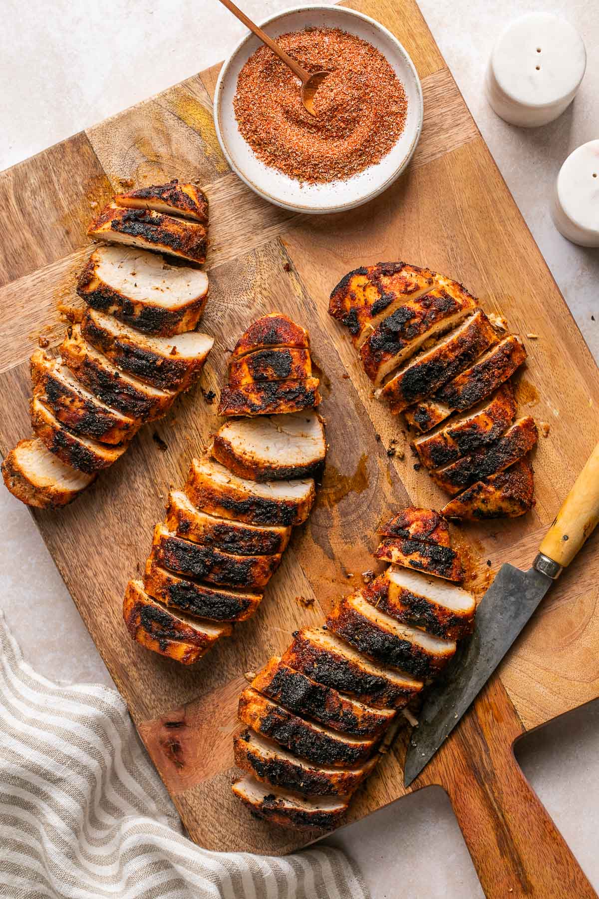 an overhead shot of cooked and slice poultry on a wooden cutting board 