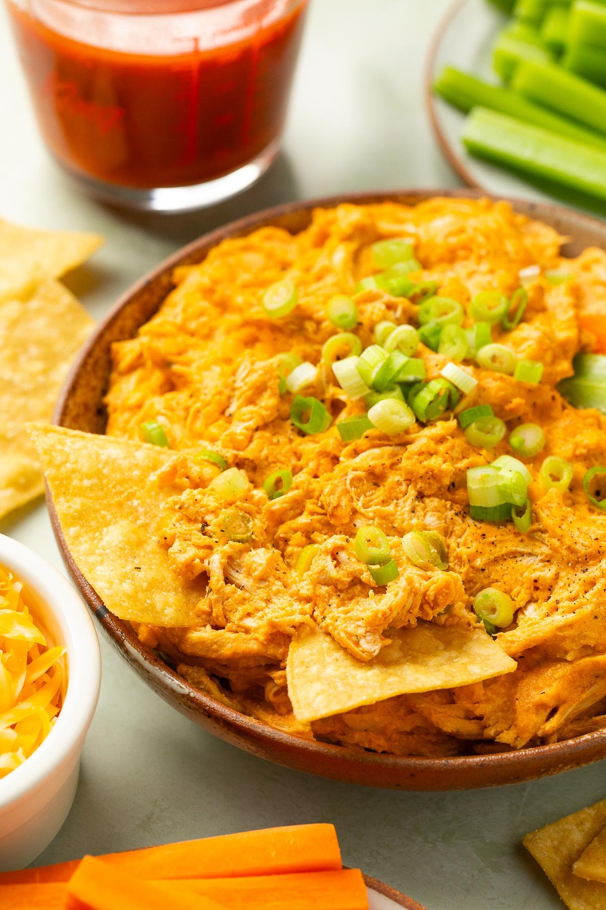 a bowl of crockpot buffalo chicken dip topped with chopped green onions