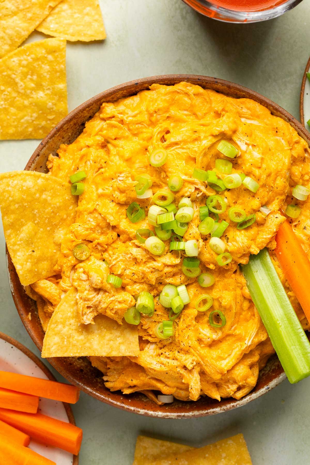 crockpot buffalo chicken dip in a bowl with tortilla chips, celery, and carrots