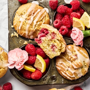 a muffin tin with muffins and fruit and flowers decorated around it.