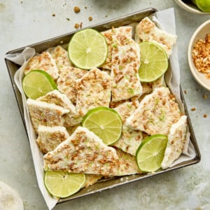 an overhead shot of yogurt bark on a baking tin with key limes on top