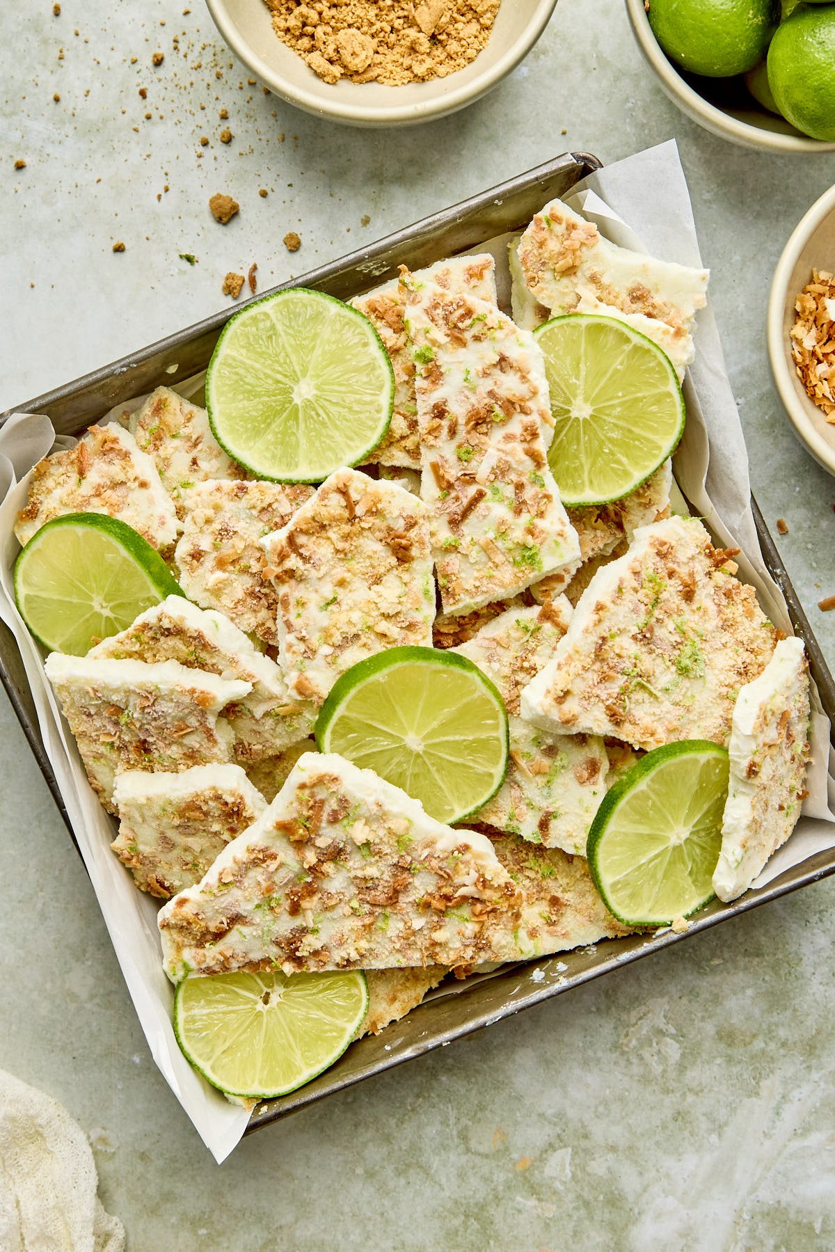 an overhead shot of yogurt bark on a baking tin with key limes on top