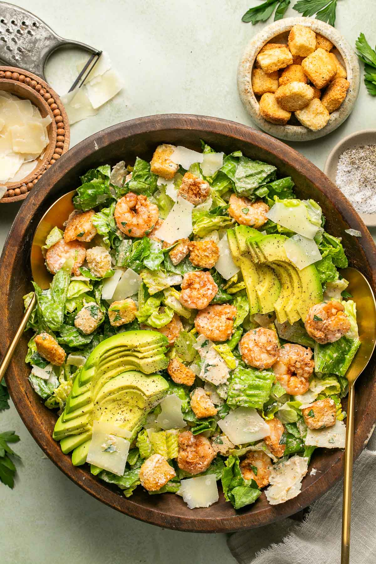 an overhead shot of a shrimp caesar salad tossed in a wooden salad bowl