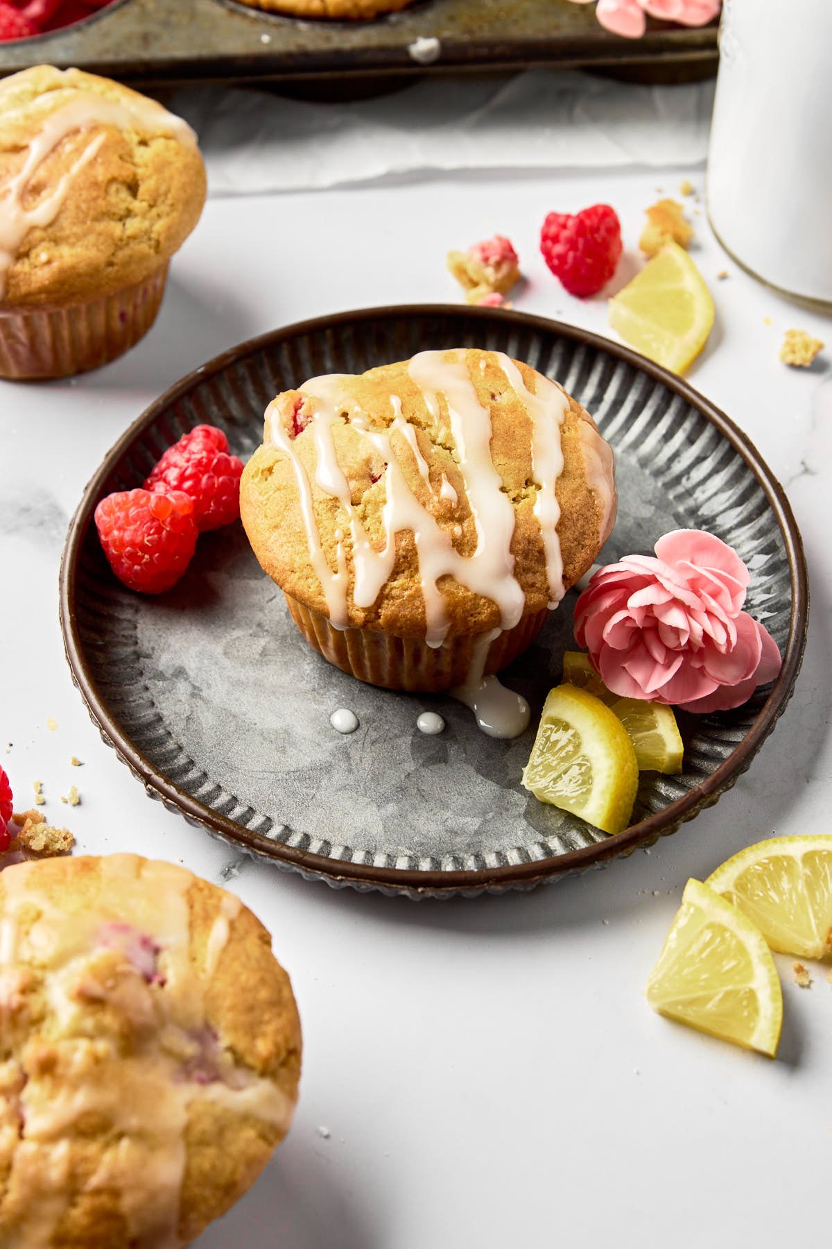 a raspberry lemon muffin on a plate drizzled with lemon glaze 