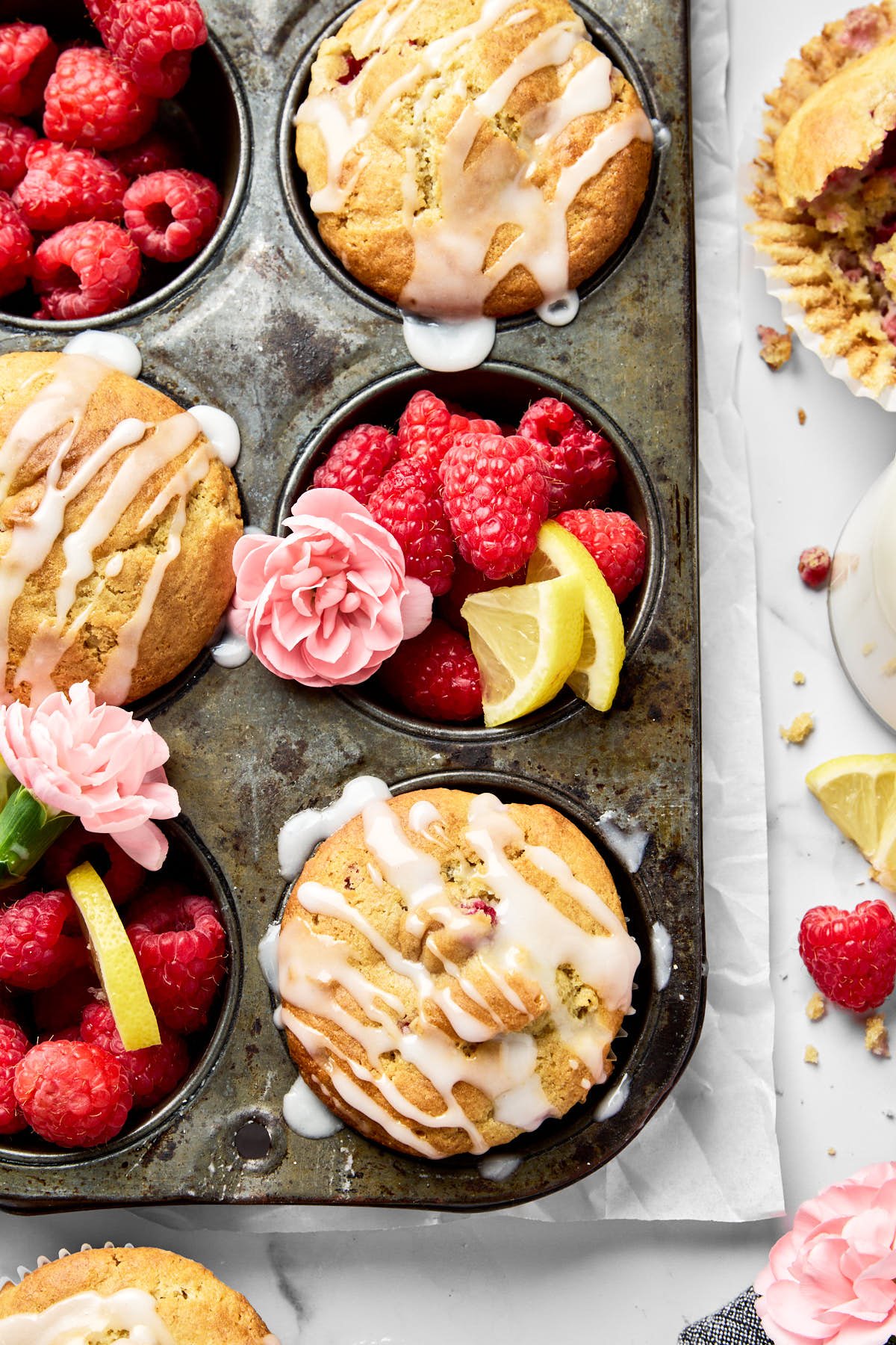 an overhead shot of raspberry lemon muffins in a muffin tin and drizzled with lemon glaze