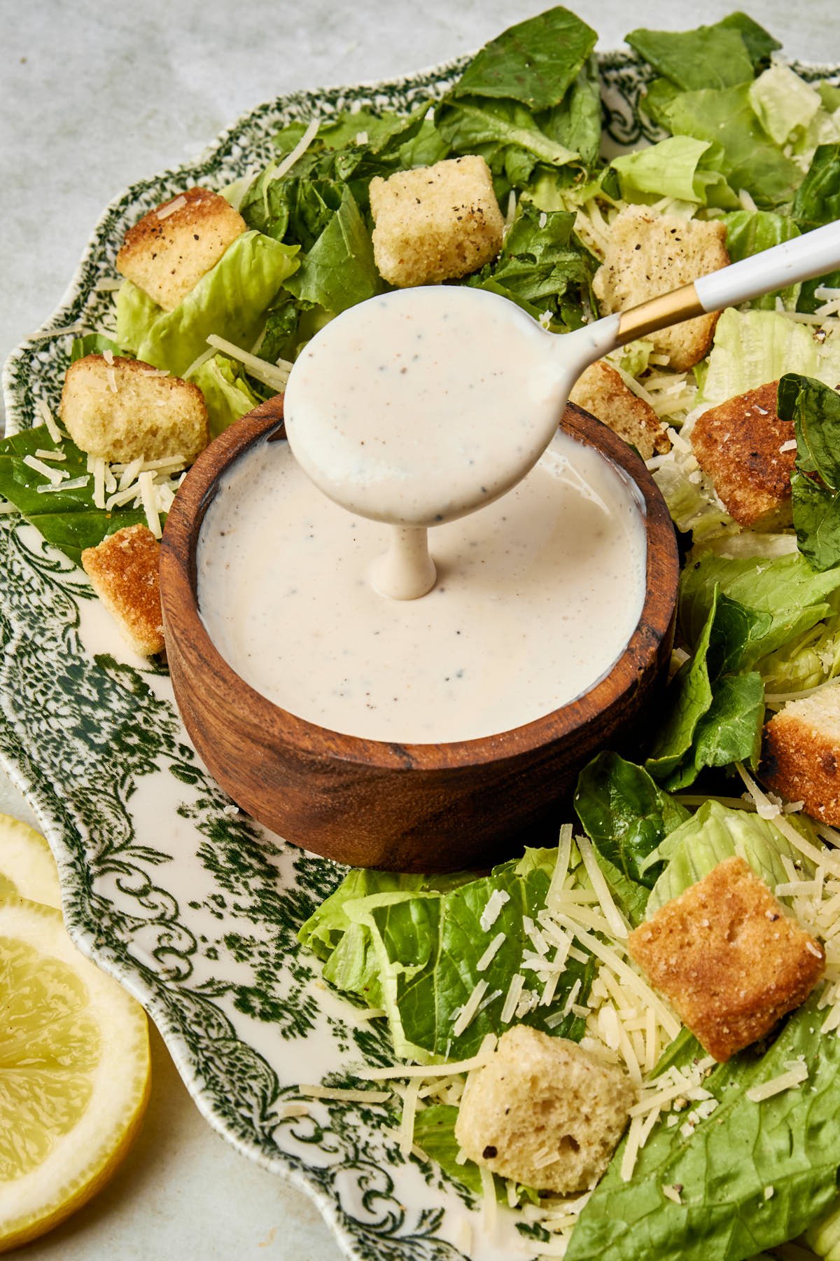 a small container of caesar dressing surrounded by a bed of lettuce